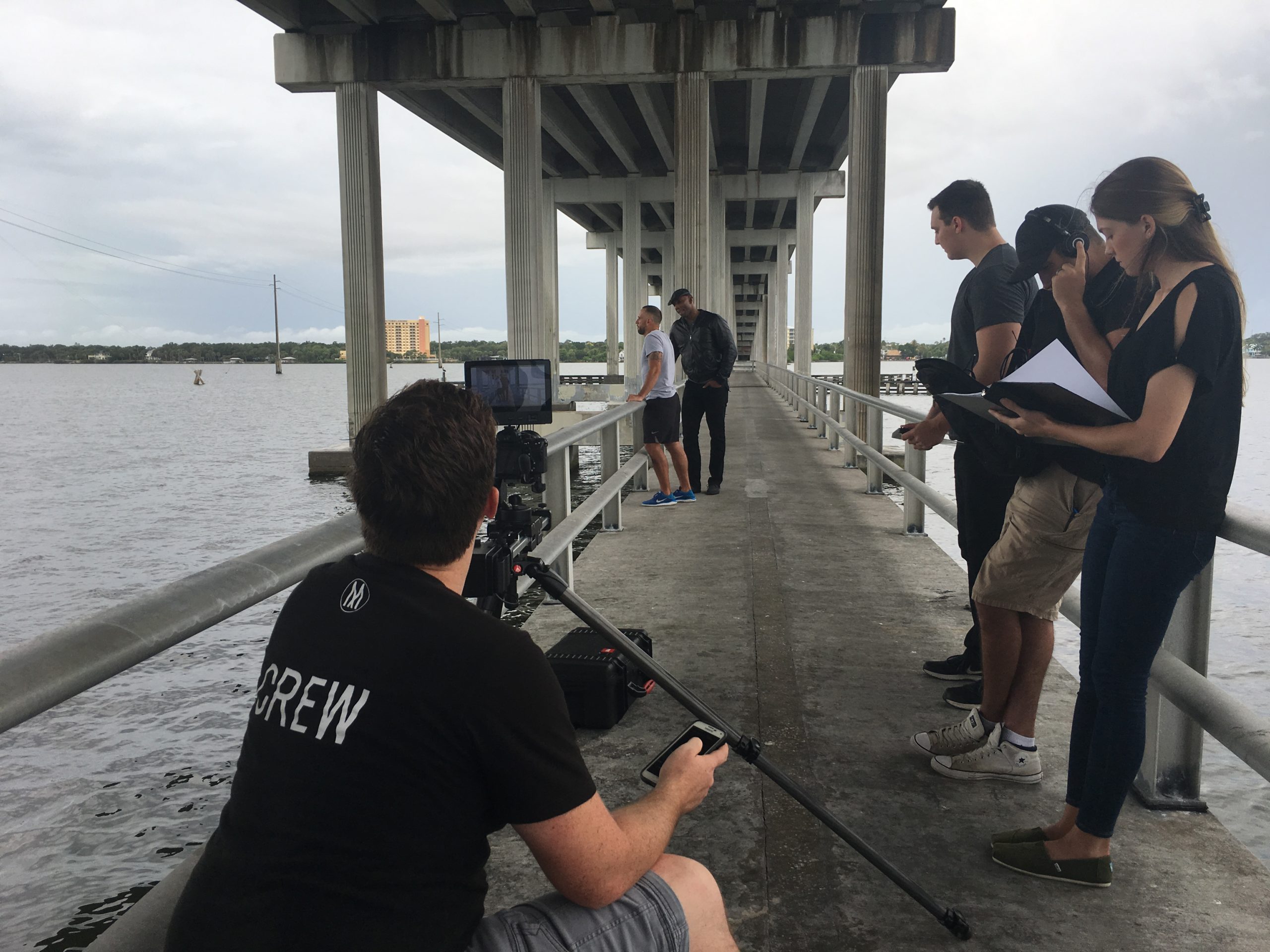 Production crew shooting a video on a pier under a bridge 